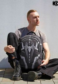 Sac à dos à thème Spider-Man noir et gris avec un emblème d'araignée, des accents en maille et plusieurs zips. Matériau texturé avec des sangles robustes.