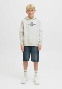 Hellgrauer Hoodie mit Logo und Vordertasche; blaue Denim-Shorts; weiße Sneakers mit strukturierten Akzenten; weiße Socken. Lässiges Outfit für Jugendliche.