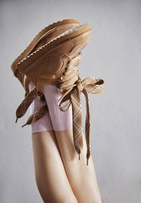 Brown suede high-top shoes with textured lace details and patterned ribbons, paired with light pink ribbed socks, positioned at an upward angle.