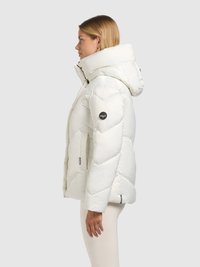 Doudoune blanche avec col montant et capuche. Présente un motif matelassé en losanges, des poignets élastiques et un patch logo rond sur la manche.