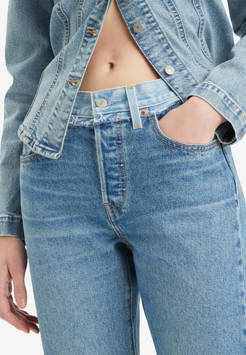 Lichtblauwe denim jeans met een hoge taille, rits en vijf zakken met contrasterende stiksels. Gecombineerd met een licht denimjack.
