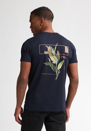 Navyblauwe katoenen t-shirt met een bloemontwerp op de rug, met groene bladeren en witte bloemen binnen een rechthoekige omlijning.