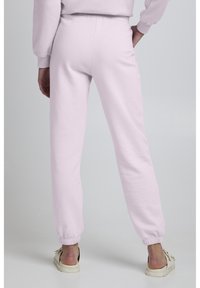 Lichtroze sweatpants met elastische tailleband en boorden, gemaakt van zachte stof. Heeft een ontspannen pasvorm en een eenvoudig ontwerp.