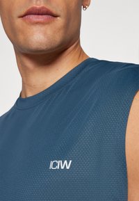Dark blue sleeveless shirt made from textured fabric, featuring the logo "ICIW" in white. The design includes a round neck and clean seams.