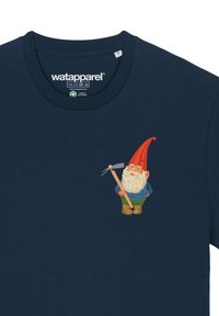 Un t-shirt marine présente un gnome de dessin animé avec un chapeau pointu rouge, une barbe blanche, une chemise bleue, un pantalon vert et tenant une fourche.