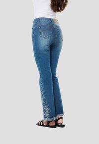 Kék farmer flared nadrág rojtos szegéllyel. Bonyolult virágos hímzés díszíti az oldalát, klasszikus ötpockets kialakítással.