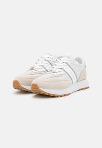 Sneaker beige in suede e mesh con dettagli bianchi, dotate di una suola texturizzata e dettaglio del logo sul lato, progettate per comfort e stile.