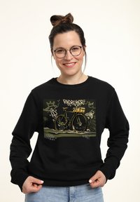Felpa nera con un grafico di una bicicletta con accenti dorati, su uno sfondo in stile graffiti verde con vari disegni.
