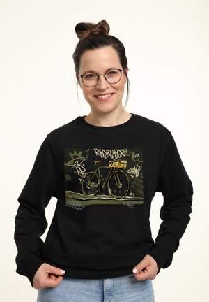 Felpa nera con un grafico di una bicicletta con accenti dorati, su uno sfondo in stile graffiti verde con vari disegni.