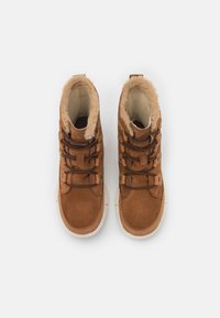 Bottines montantes en faux daim marron avec une doublure en fausse fourrure, des lacets texturés et des œillets en métal. Semelles en caoutchouc de couleur crème.