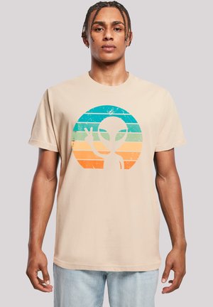 Beige Baumwoll-T-Shirt mit einem verwitterten Alien-Graphic in einem türkisfarbenen, orangen und blauen Kreisdizern, das ein Friedenssymbol zeigt. Kurze Ärmel, lockere Passform.