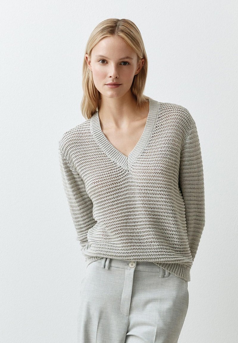 Hellgrauer, gestrickter Pullover mit V-Ausschnitt, der ein texturiertes Muster und gerippte Bündchen aufweist. Kombiniert mit hellgrauen, maßgeschneiderten Hosen.