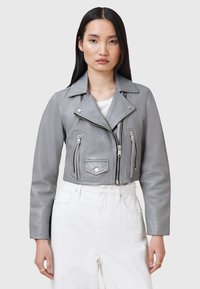 Giacca moto cropped in pelle grigia con colletto a rever, cerniera asimmetrica e tasche frontali con zip. Presenta una texture liscia e un design aderente.