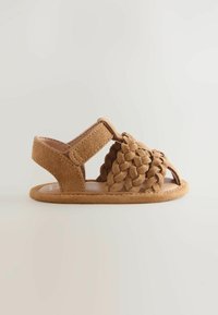 Sandale bébé en daim marron avec des lanières avant tressées et une bride de cheville Velcro sur un fond uni.