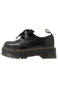 Scarpe stringate in pelle nera con una spessa suola platform in gomma trasparente, caratterizzate da cuciture gialle e un fiocco in satin nero sui lacci.