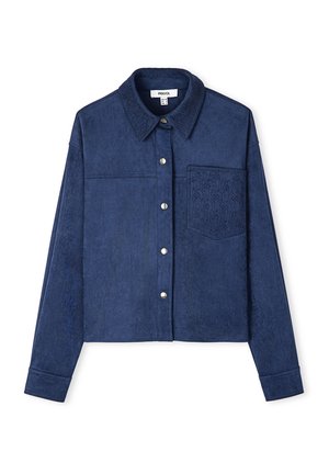 Dunkelblaue, kurz geschnittene Jacke aus weichem, strukturiertem Stoff mit Knopfverschluss und einer gestickten Tasche, die ein geometrisches Muster zeigt.