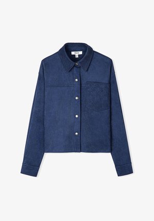 Giacca cropped blu scuro in tessuto morbido e testurizzato, con chiusura a bottone e una tasca cucita con un motivo geometrico.