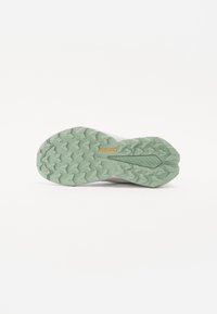 Schuhsohle mit einem strukturierten Design, das grünes Gummi und ein markantes Continental-Logo aufweist. Die Traktionselemente sind auffällig geformt.