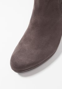 Botín de ante gris con punta redondeada y textura suave. El diseño presenta líneas minimalistas sin herrajes ni acentos visibles.