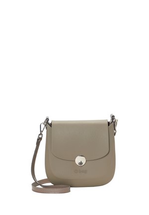 Pieni taupenvärinen olkalaukku, jossa läppäkiinnitys, hopeanvärinen pyöritettävä lukko ja irrotettava olkahihna, jonka etuosassa on "O bag" -merkintä.