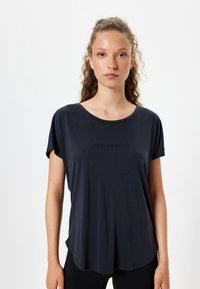 Mørk navy kortærmet t-shirt med rund halsudskæring og løs pasform, med et trykt tekstdesign i midten. Glat stofstruktur.