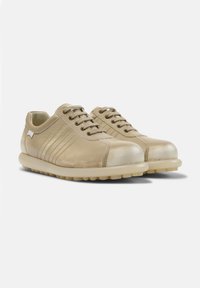 Zapatillas de cuero beige con un acabado brillante, que cuentan con una puntera reforzada, rayas laterales texturizadas y una suela de goma con patrón de tracción circular.