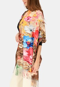 Kolorowy kwiatowy szal z żywymi kwiatami w odcieniach różu, niebieskiego i żółtego na brązowym tle, z frędzlami na brzegach dla dodatkowej faktury.
