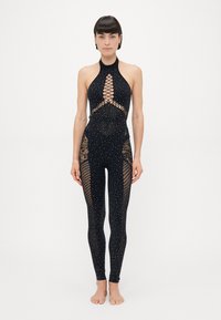 Black jumpsuit with a halter neck, featuring lace cutouts and studded details. Slim-fit design with a textured pattern on the legs.