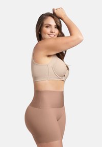 Beige naadloze bh met brede banden en zachte cups, gecombineerd met hoge, gladde bruine shapewear-shorts, die een minimalistisch ontwerp laten zien.