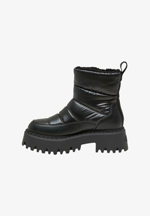 Bottes noires à la cheville avec un design rembourré, en cuir brillant. Semelle en caoutchouc épaisse avec un motif à bord coupant. Boucle à l'arrière pour un enfilage facile.