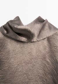 Tissu froissé dans une teinte métallique bronze atténuée, doté d'un design de col drapé doux avec une surface texturée.