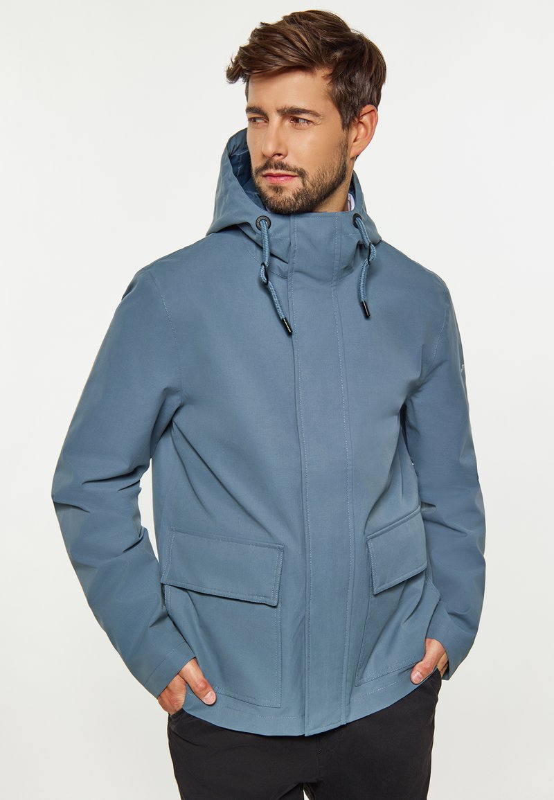 Veste bleue imperméable avec capuche, deux poches avant, cordon ajustable et design structuré. Texture lisse avec finition mate.