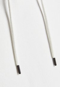Tessuto di felpa bianco con due cordini; ogni cordino presenta terminali in plastica nera per garantire durata e facile regolazione.