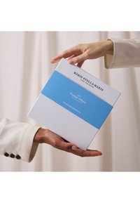 Boîte cadeau blanche avec bande bleue étiquetée « Voyage Vétiver ». Présente le nom de la marque « MARIE-STELLA-MARIS » sur le dessus, finition mate, forme rectangulaire.