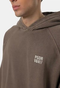 Felpa con cappuccio in morbido tessuto marrone tenue. Presenta un logo bianco sul petto. Vestibilità casual con dettagli a coste.