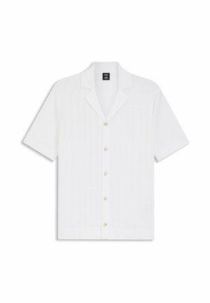 Camicia bianca a maniche corte con bottoni, linee verticali strutturate e colletto a lancia, distesa su uno sfondo bianco.