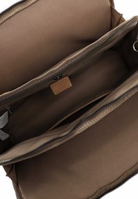 Brown fabric interior of a bag with two zippered compartments, smooth texture, and a small leather tag visible on the side.
