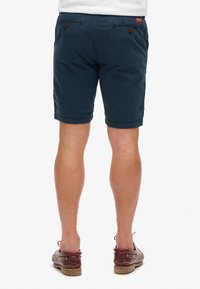 Marineblauwe shorts van katoen, met zijzakken en achterzakken met knoop. De zoom is gestikt voor een nette afwerking.