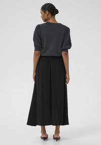 Hallitatud hall ribadega puff-sleeve topp, mille juurde on sobitatud pikk must seelik, millel on elastne vöökoht ja sile tekstuur. Minimalistlik disain, ilma mustriteta.