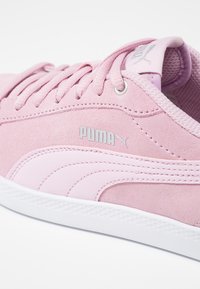 Puma rosa sneakers har en ovandel i mocka, tonade snörningar, en gummisula och en silverfärgad logotyp som accent på sidan för kontrast.