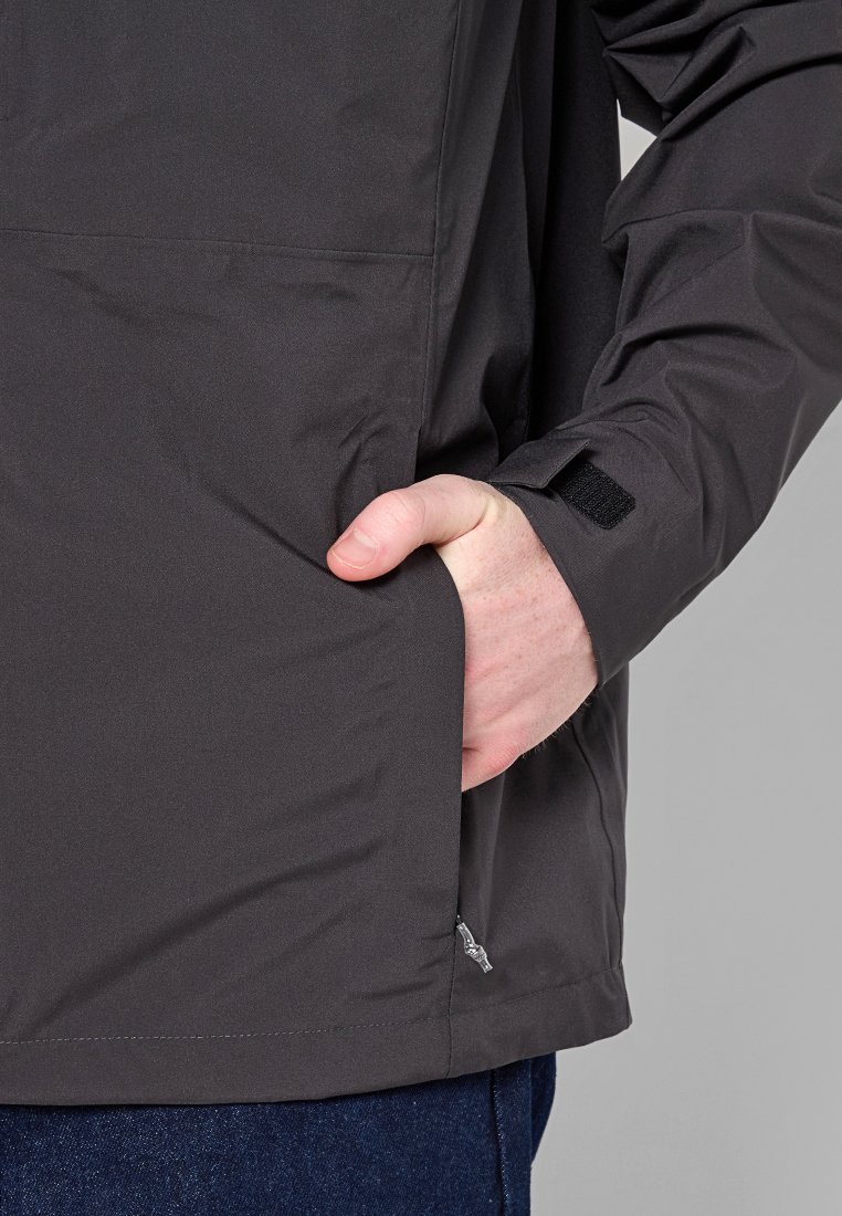 Chaqueta impermeable gris con una textura suave, que cuenta con un bolsillo lateral, puños ajustables con velcro y un corte ligeramente entallado en la cintura.