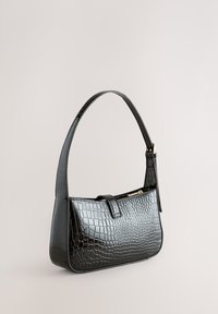 Sac à main en similicuir noir à texture crocodile, avec une anse incurvée et un petit rabat avant. Présente un accent de fermeture éclair dorée.