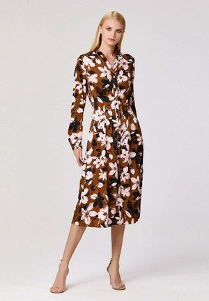 Robe florale marron à manches longues, avec fermeture à boutons et taille cintrée. Présente de grandes fleurs blanches et roses sur un fond sombre.