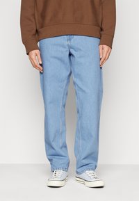 Helle blaue gerade Jeans mit klassischem Fünf-Taschen-Design, aus Denim-Stoff, kombiniert mit weißen Sneakern.