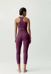 Lila träningsset som består av en sport-bh med racerback och högmidjade leggings med texturerade paneler och en slät yta.