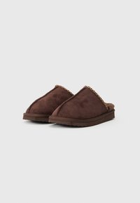 Pantofole in suede marrone con punta arrotondata, caratterizzate da un interno texture e un dettaglio intrecciato lungo il bordo superiore. Suola piatta in gomma.