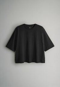 Czarny T-shirt z krótkim rękawem wykonany z miękkiej bawełny, z okrągłym dekoltem i luźnym krojem oraz lekko zaokrąglonym dołem.