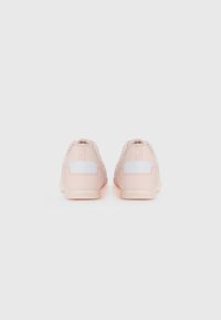 Un paio di sneakers rosa chiaro con dettagli bianchi, viste da dietro su uno sfondo bianco semplice.