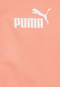 Svijetlopinkasti materijal s teksturiranom površinom na kojoj se ističe istaknuti bijeli PUMA logo i silueta skočnog pume.