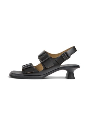 Sandale noire à bout ouvert avec trois brides réglables à boucle, talon bas incurvé et design slingback sur fond blanc.